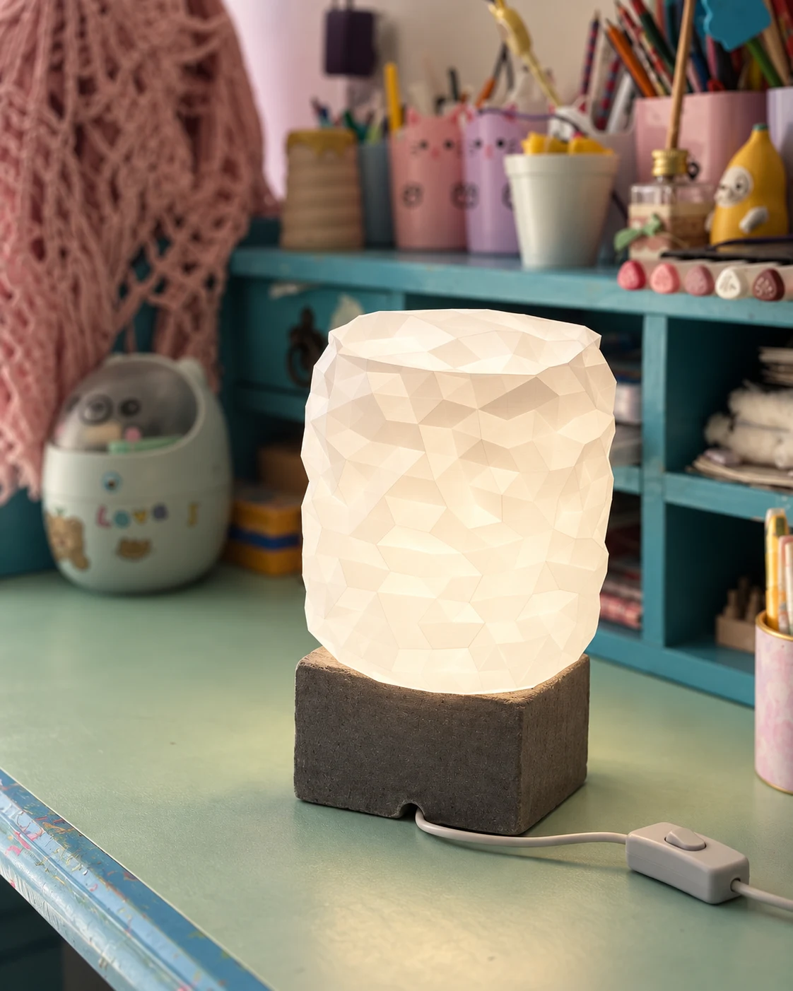 Luminária branca facetada com base escura, em um cantinho da nossa casa